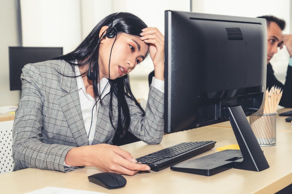A man in business casual clothes sitting at a desk reviewing rental documents with a laptop and calculator in an office.