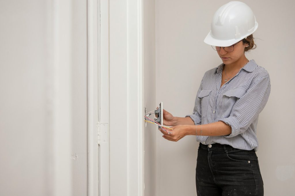 Woman performing a property inspection on the electrical system as part of the due diligence when buying a rental property.