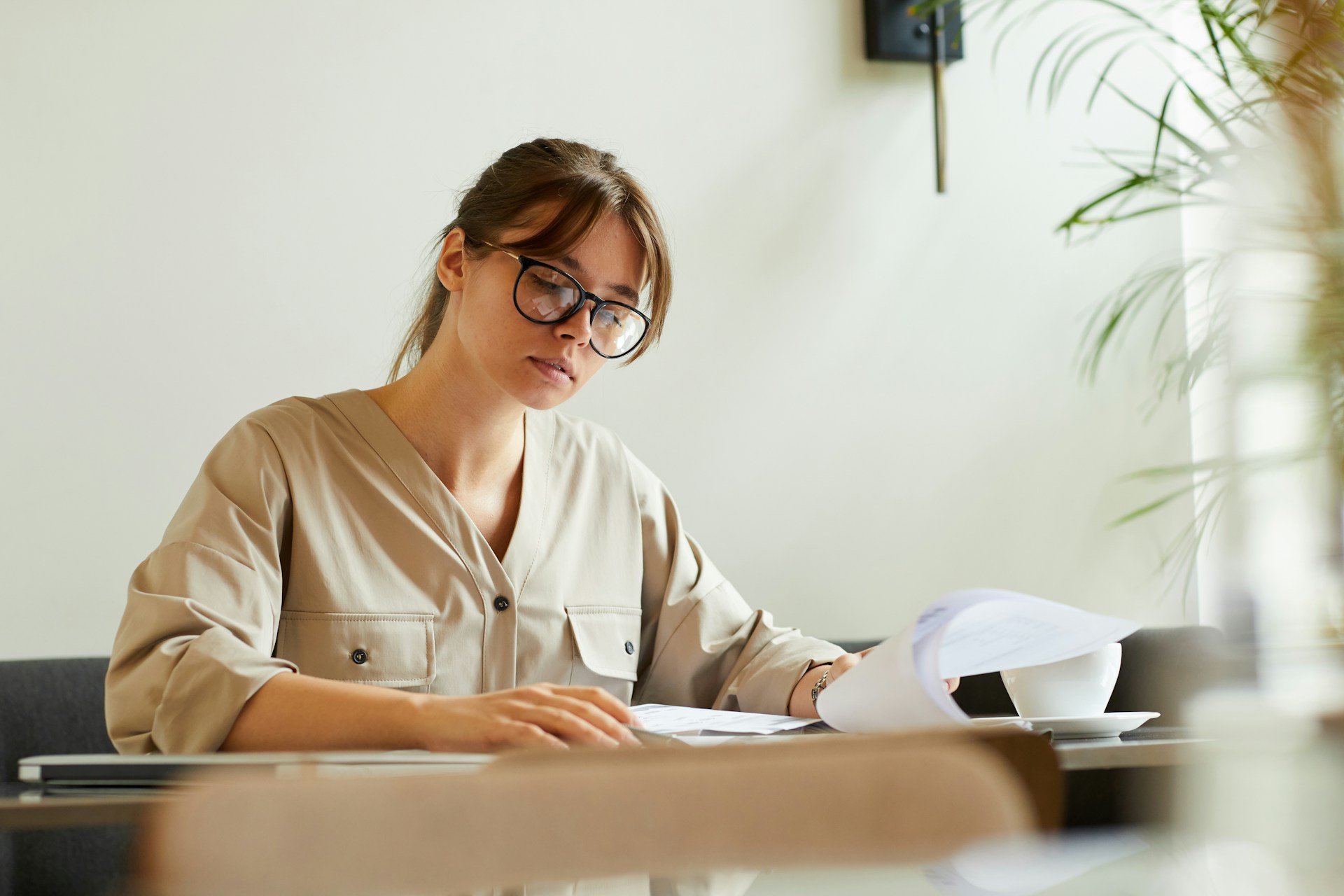 A woman with a ledger with two columns, one labeled "accrual" and the other "cash-based," surrounded by stacks of property documents and financial statements