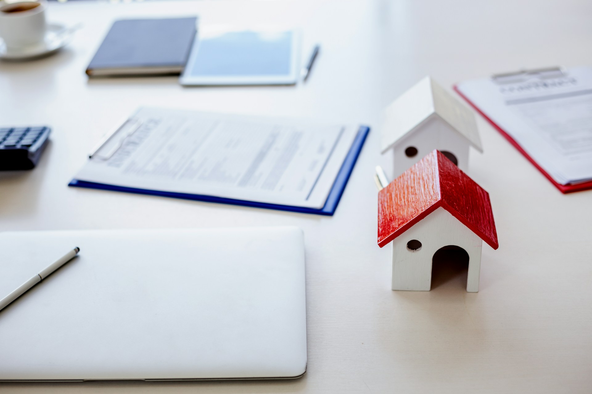 A landlord's desk with a house, rent data, and a computer used to estimate the rental price.