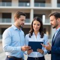 A real estate investing team standing in front of a vacant building discussing the investment opportunity the property represents.