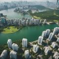 Aerial view of bustling city with skyscrapers and residential buildings surrounded by green spaces and bodies of water