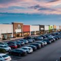 A row of modern retail buildings in a busy shopping mall and parking lot