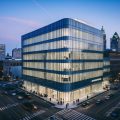 An office building with a sleek, modern design, surrounded by bustling city streets and filled with professionals going about their business