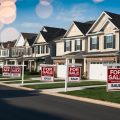 A group of houses lined up in a suburban neighborhood, with "For Sale" signs displayed in front of each property