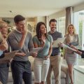 A group of people in a house engaged in a competitive real estate bidding process with a real estate agent present.