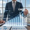 A business professional reviewing real estate market data with graphs and city buildings visible through office windows.