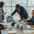 A group of investors analyzing real estate market data around a conference table with laptops and charts.
