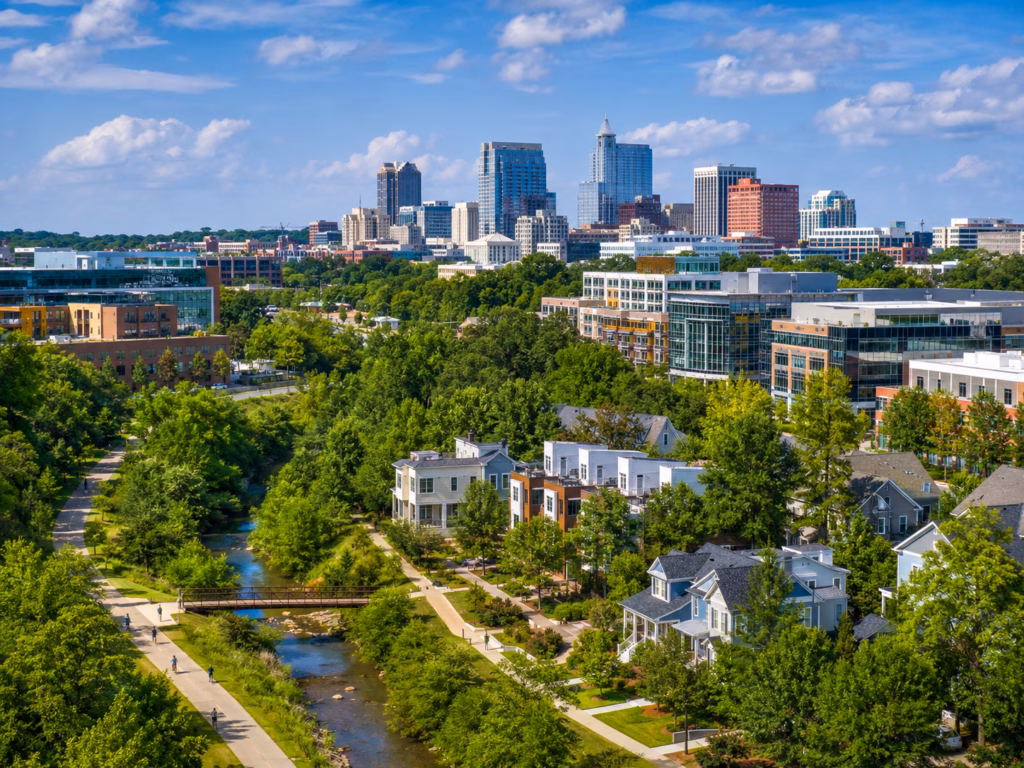 Raleigh-Cary market view with modern buildings, green residential areas, trails, and a compact downtown skyline.